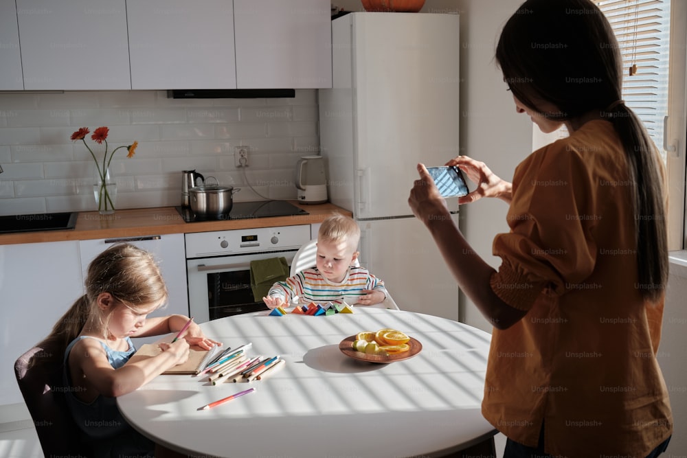 a woman taking a picture of two children at a table
