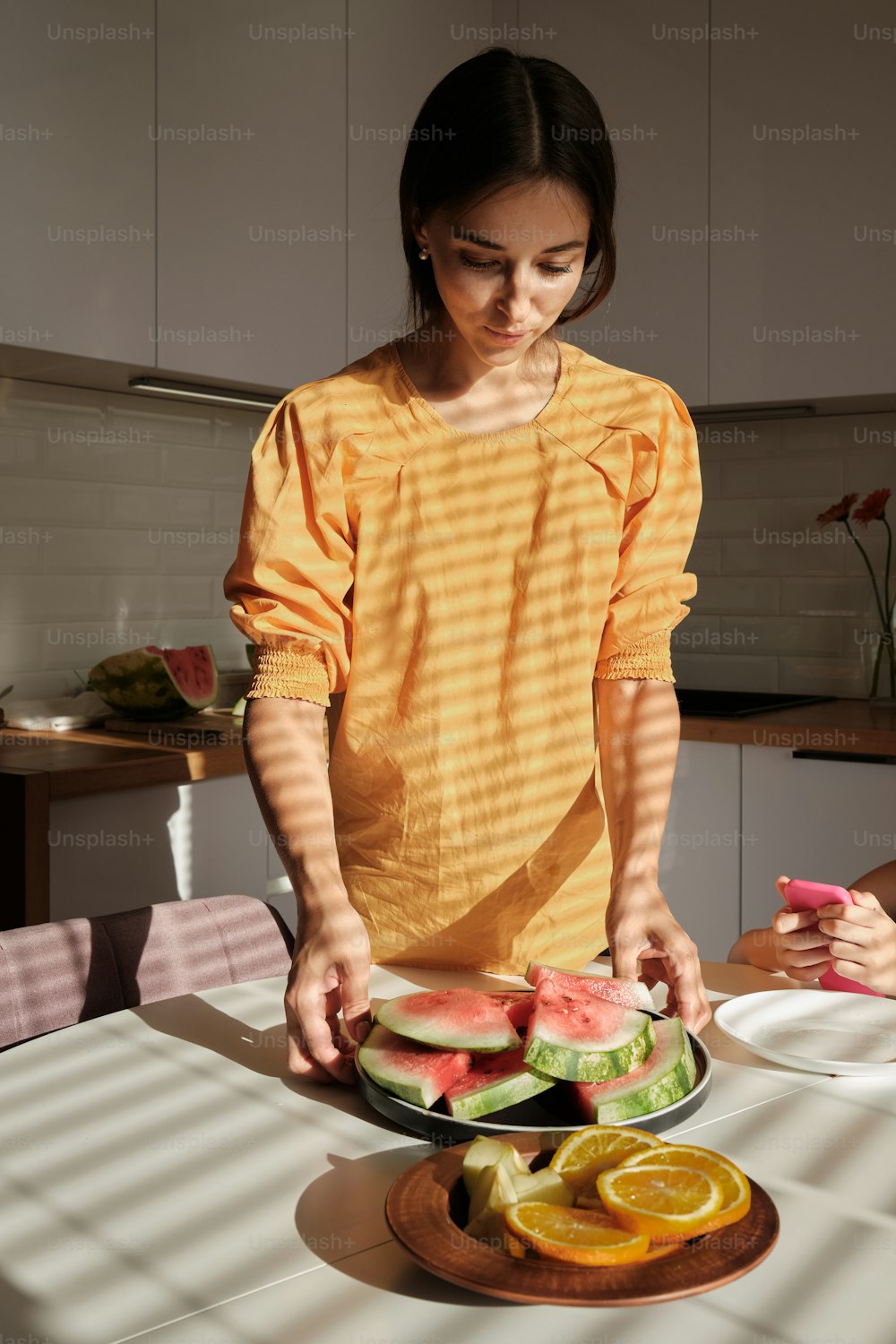 a woman cutting up a watermelon slice on a plate