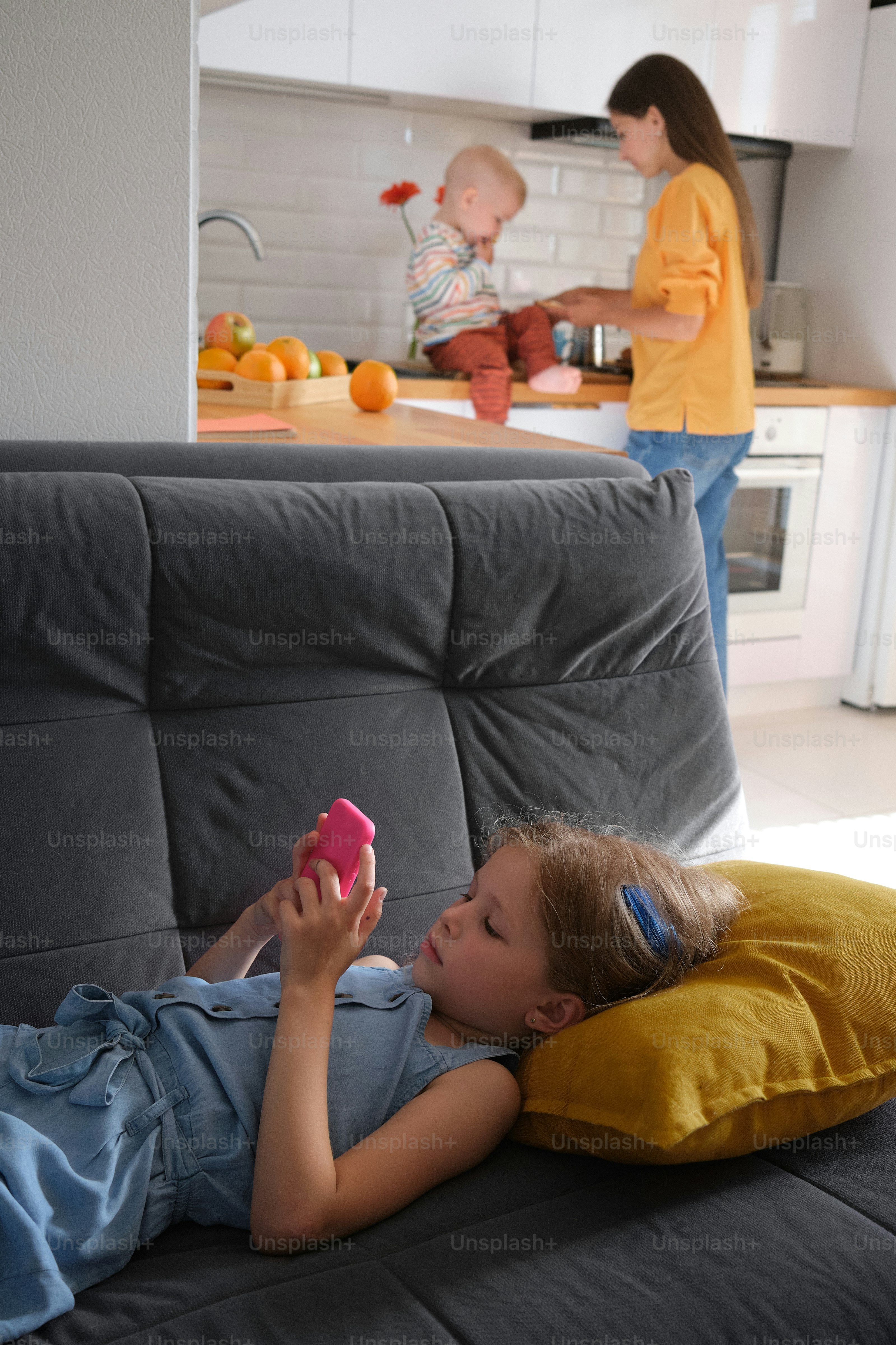 Ein kleines Mädchen, das auf einer Couch liegt und ein Handy hält