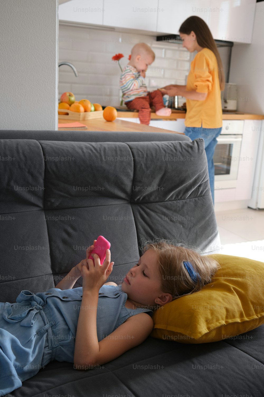 a little girl laying on a couch holding a cell phone
