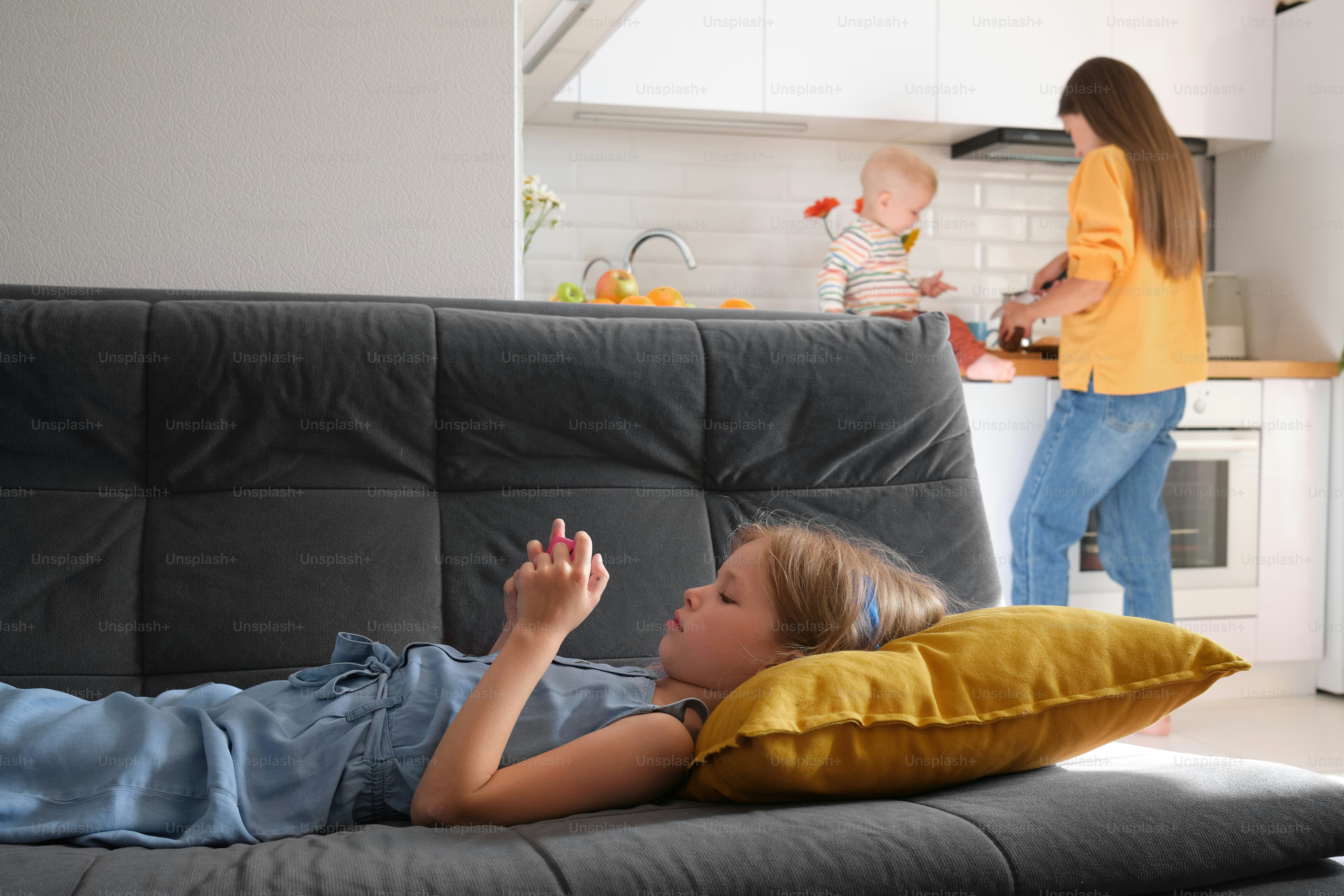 Ein kleines Mädchen, das neben einer Frau auf einer Couch liegt
