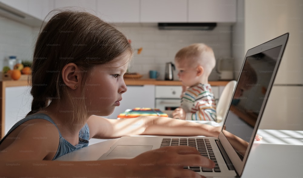 Una niña sentada frente a una computadora portátil