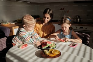 um grupo de crianças sentadas ao redor de uma mesa comendo comida