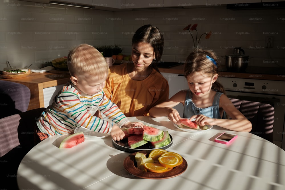 Un grupo de niños sentados alrededor de una mesa comiendo alimentos