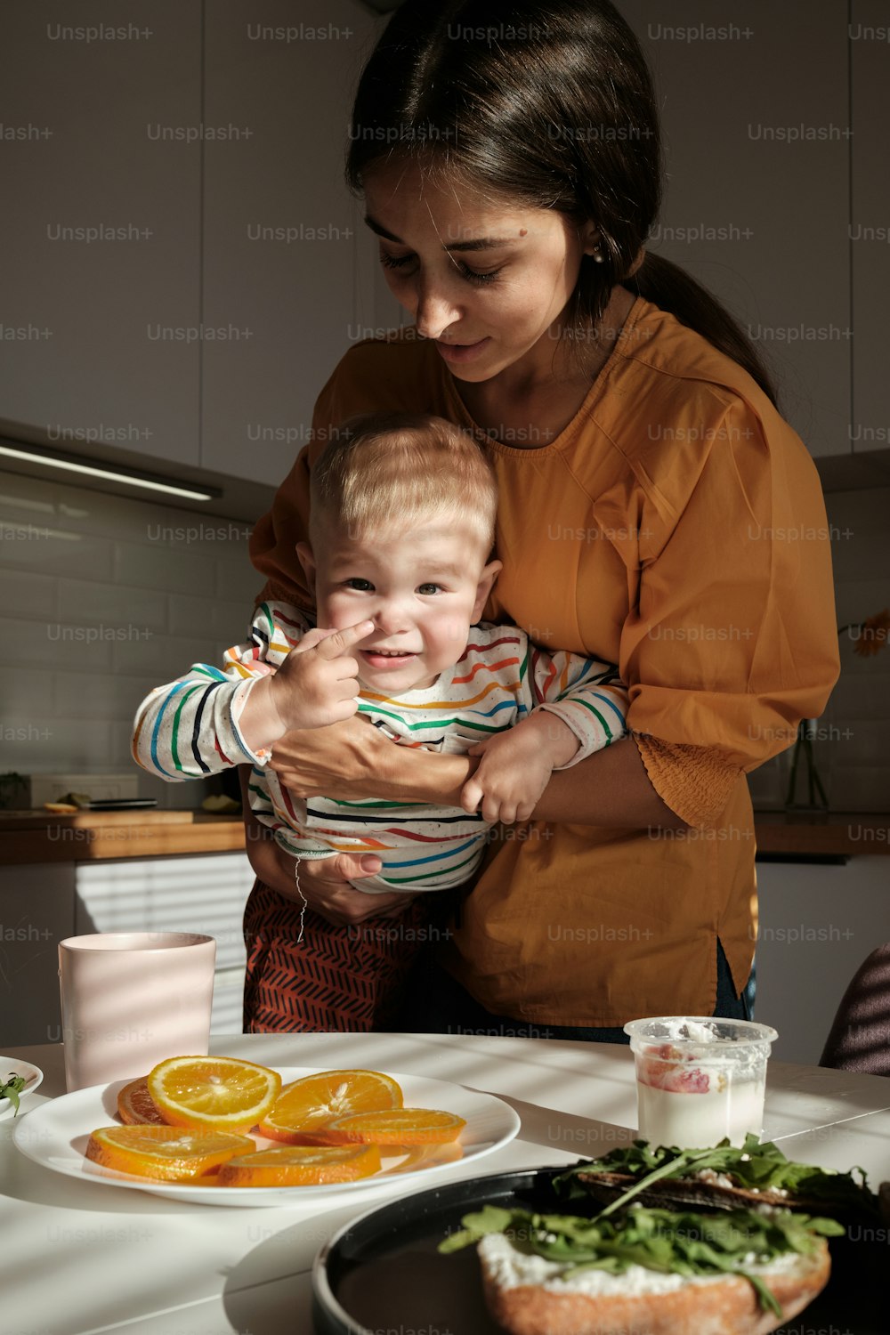 a woman holding a baby in front of a plate of food