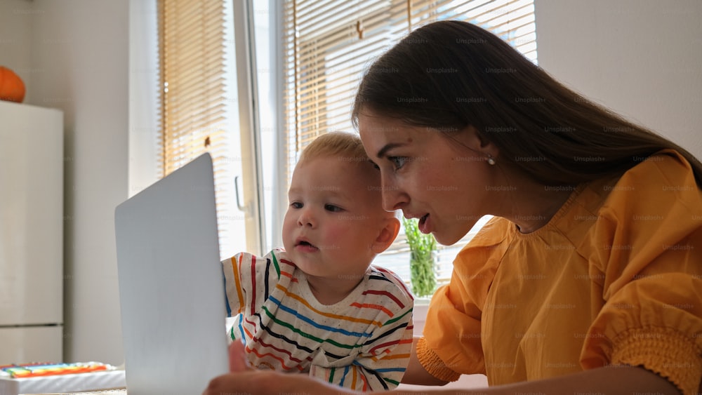 a woman and a child are looking at a laptop
