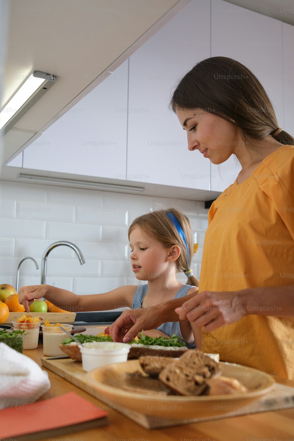 a woman and two children preparing food in a kitchen