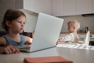 un jeune enfant assis à une table à l’aide d’un ordinateur portable