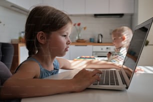 노트북 컴퓨터 앞에 앉아 있는 어린 소녀