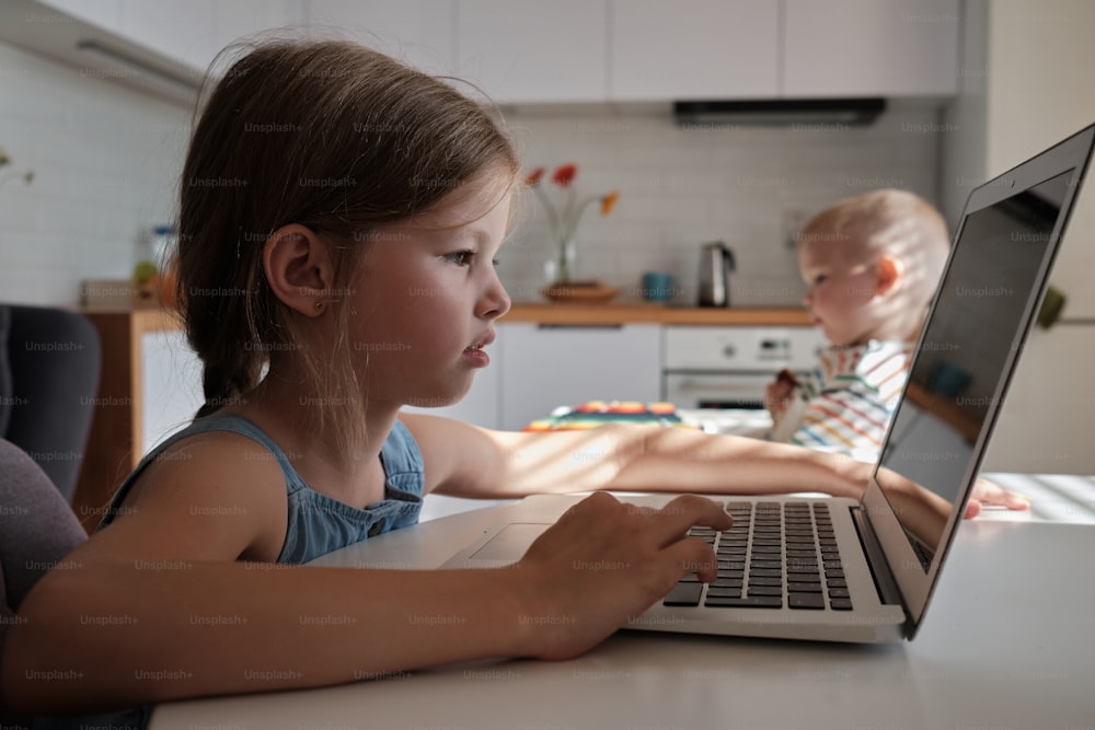 a little girl sitting in front of a laptop computer