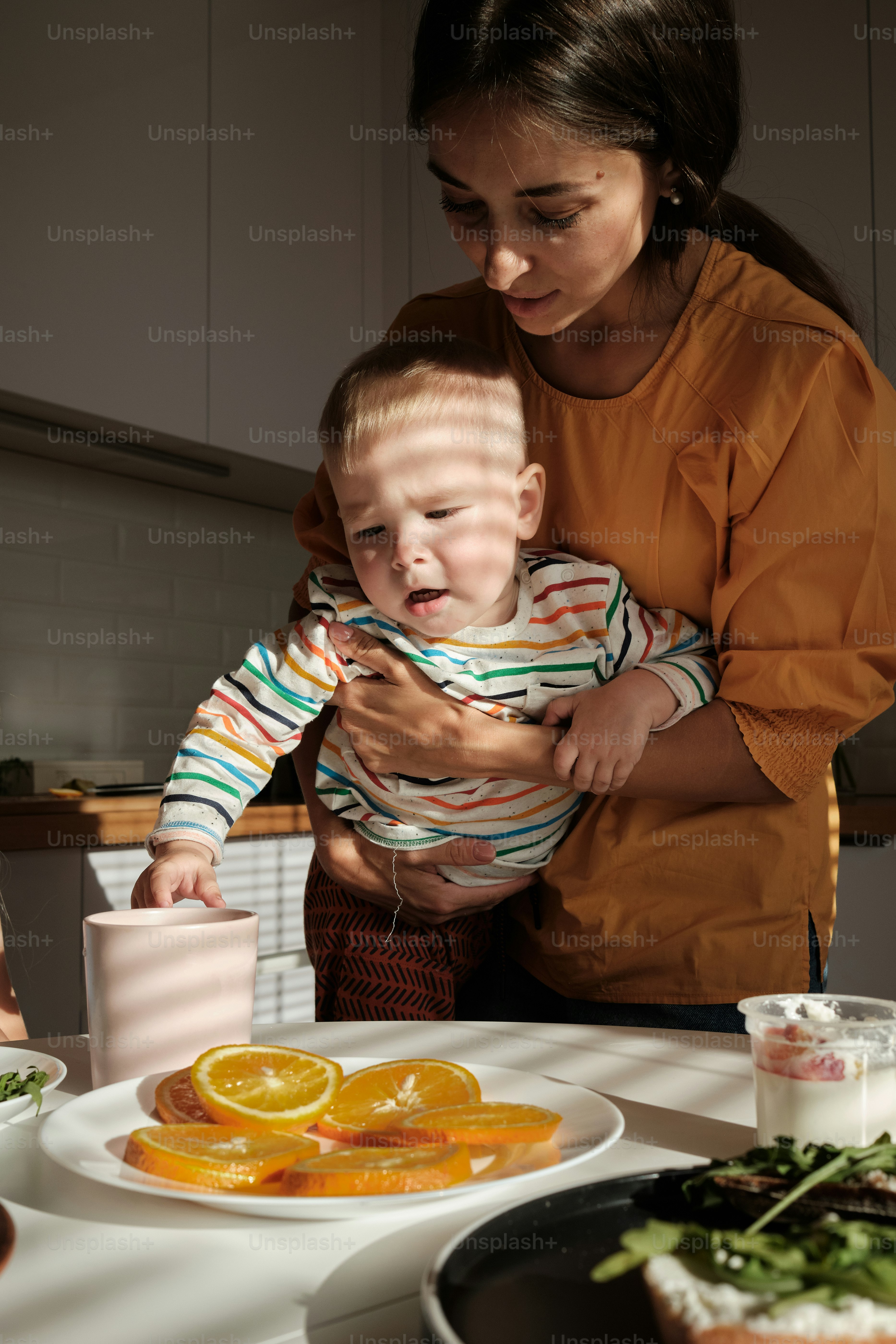 a woman holding a baby in front of a plate of food