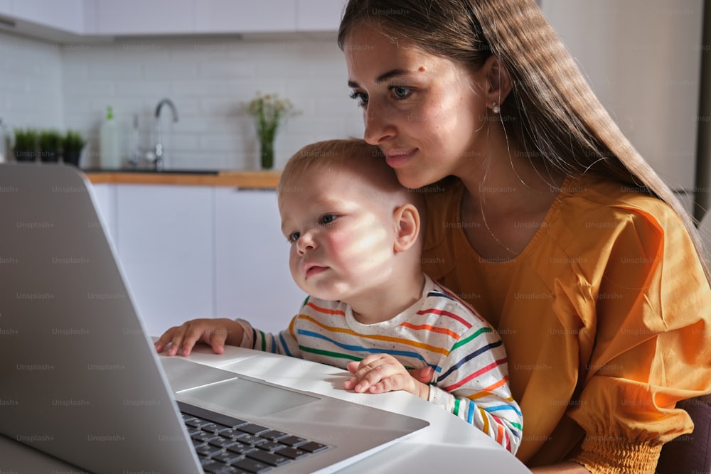 a woman and a baby are looking at a laptop