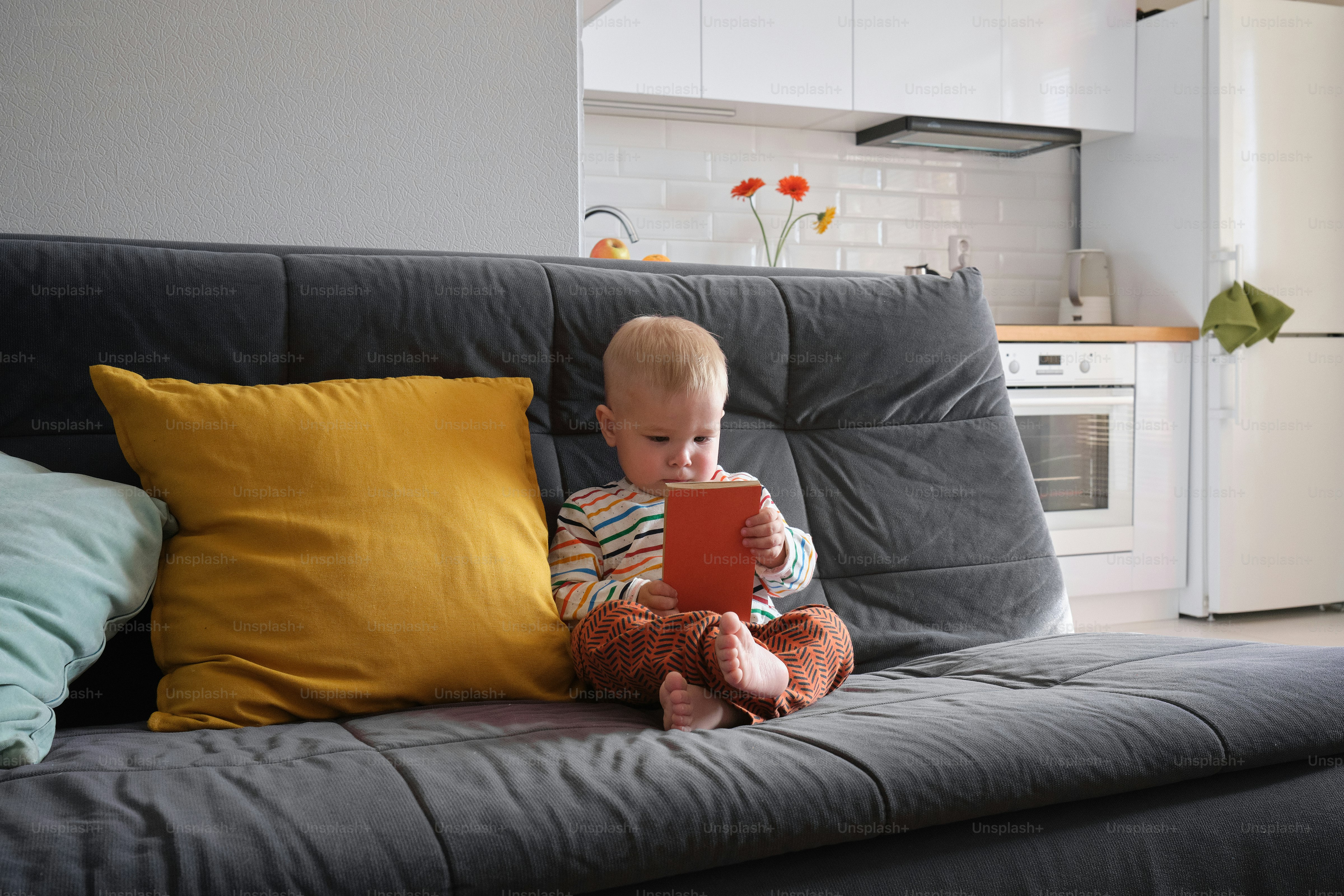a baby sitting on a couch playing with a tablet