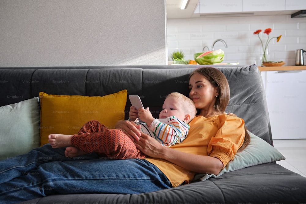 a woman sitting on a couch holding a baby