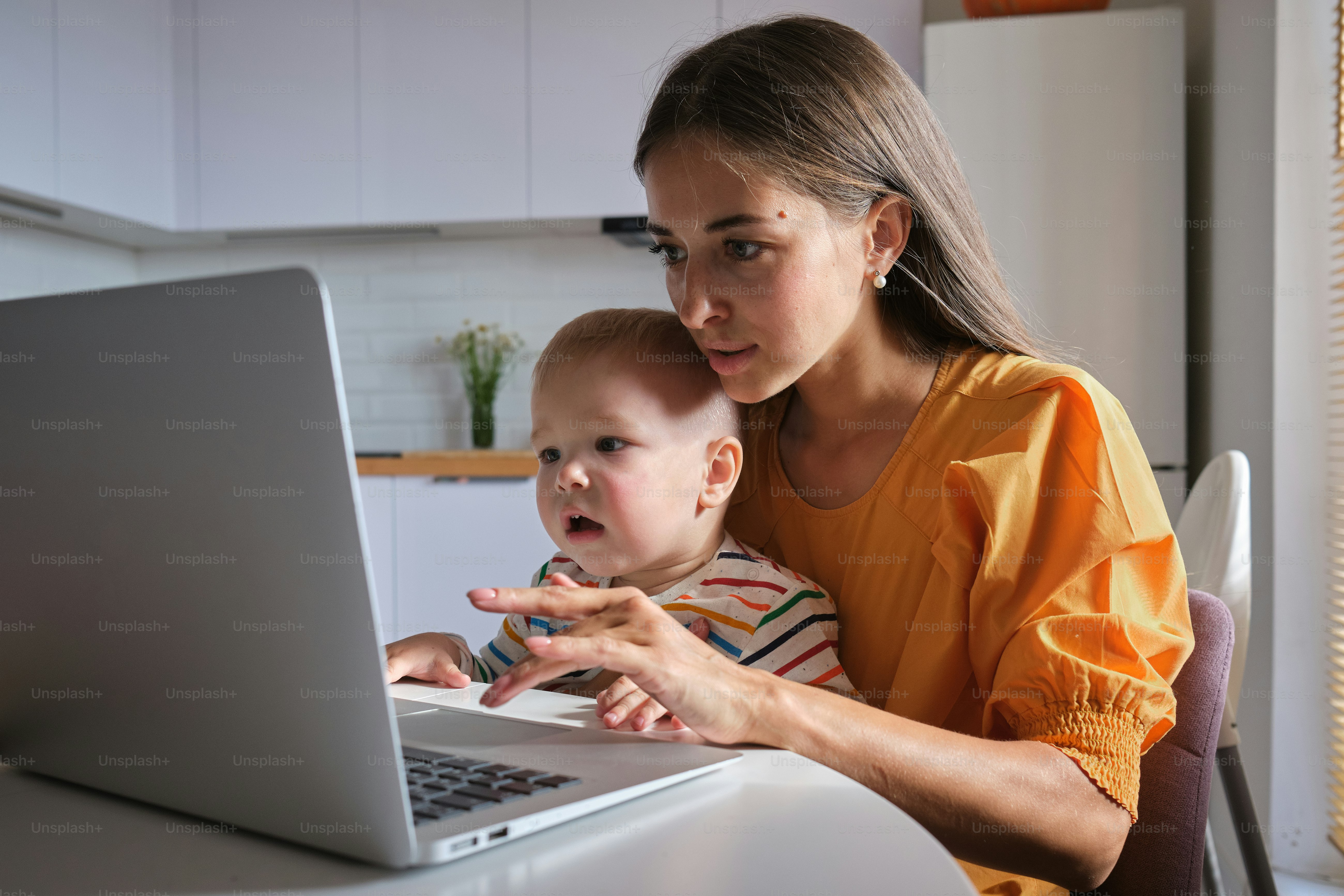 eine frau, die ein baby mit einem laptop-computer hält