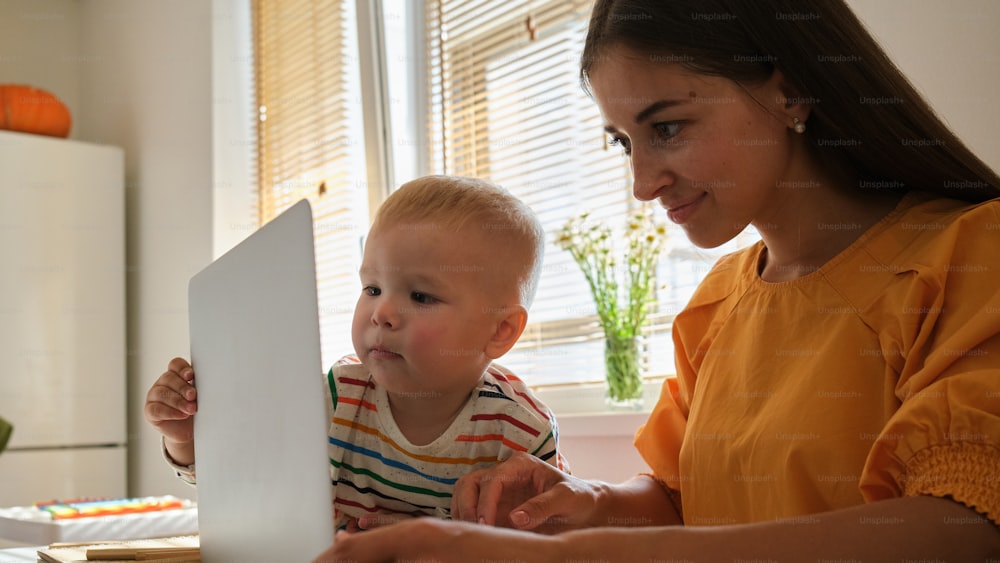 a woman and a child are looking at a laptop
