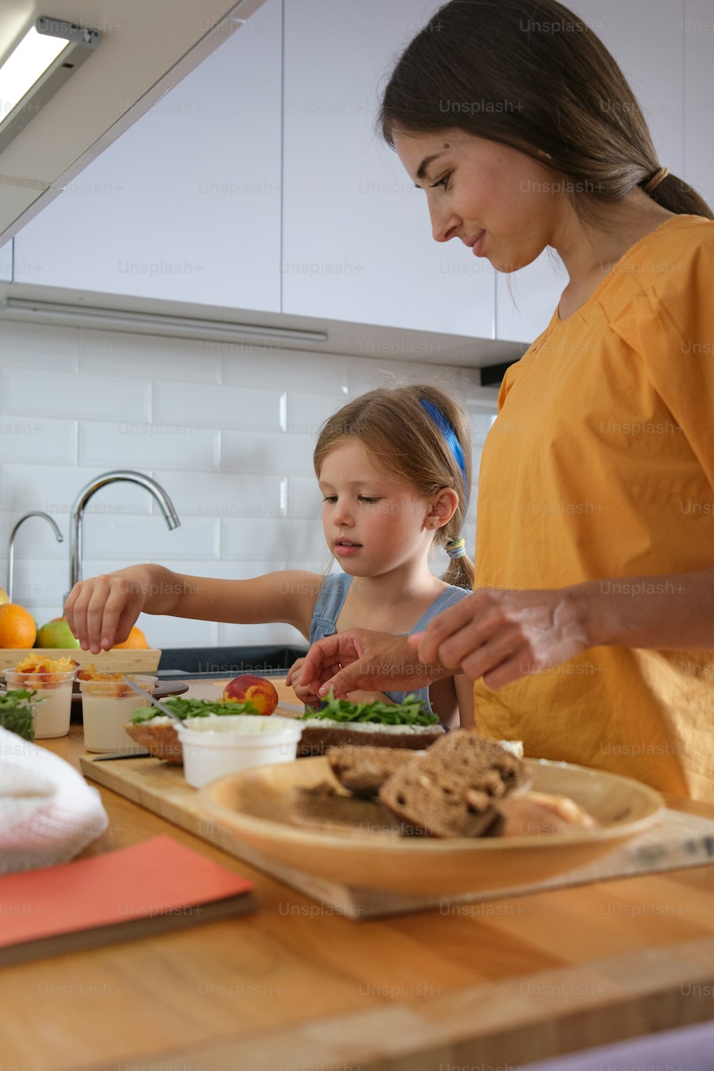 a woman and a little girl preparing food in a kitchen