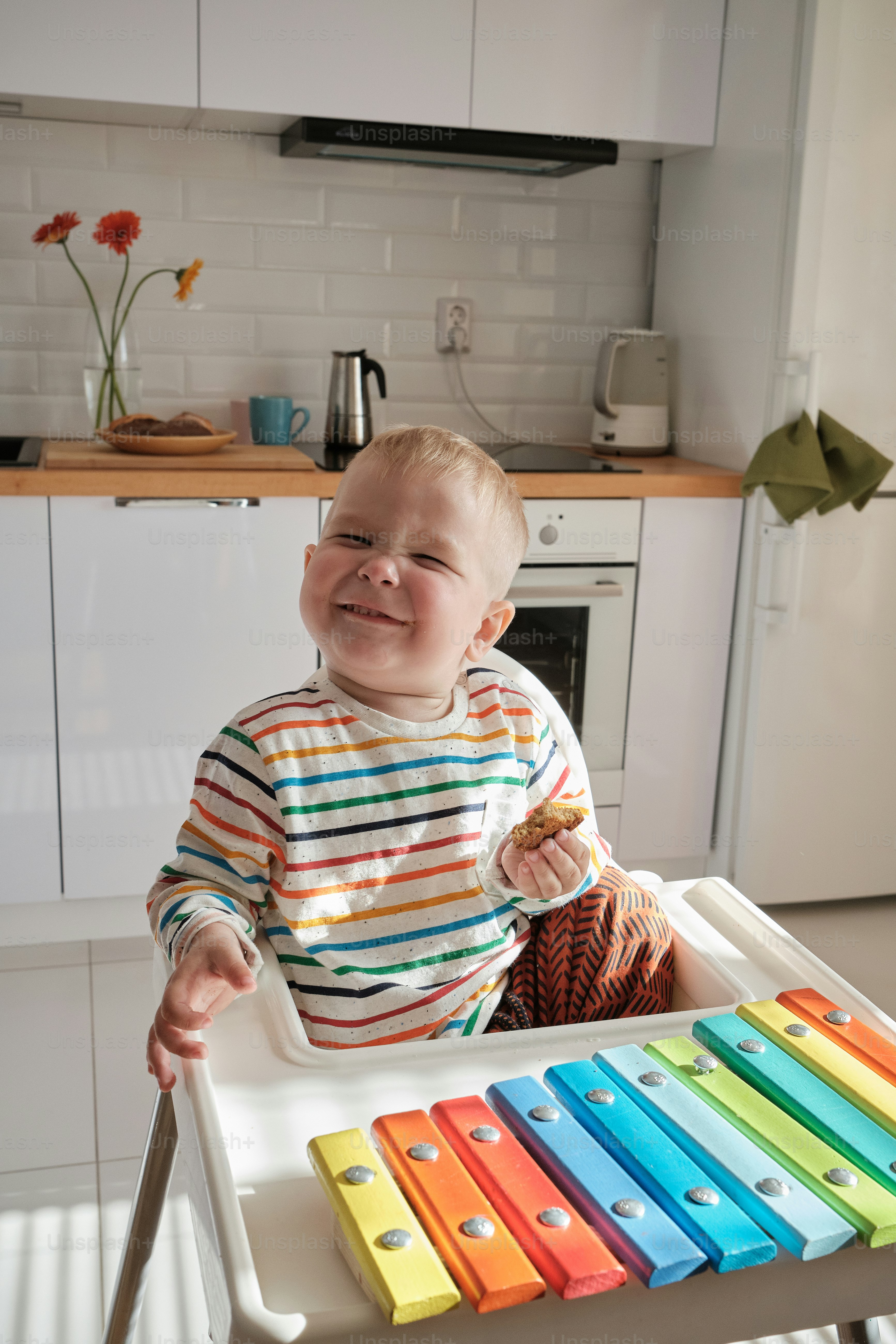 a baby sitting in a high chair holding a toy
