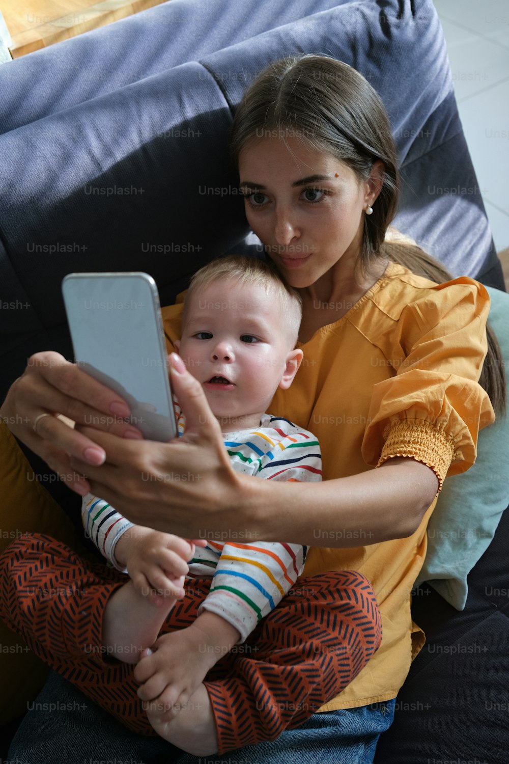 a woman holding a baby and looking at a cell phone