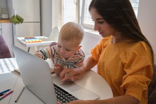 a woman holding a baby and looking at a laptop