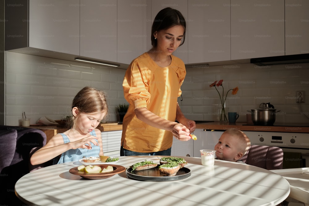 a woman and two children sitting at a table with food