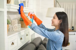 Une femme avec des gants de nettoyage utilisant un désinfectant en spray imbibé d’alcool pour nettoyer la maison, saine et médicale, concept de protection covid-19 à la maison.