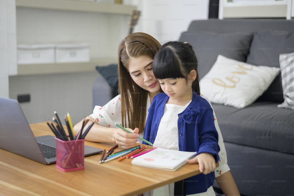 Asian Happy Mama und Tochter benutzen Laptop für das Lernen online über das Internet zu Hause. E-Learning-Konzept während der Quarantänezeit.