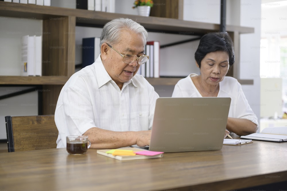 Ein glückliches älteres asiatisches Paar verbringt Zeit damit, im Internet zu surfen und mit der Familie über die Webcam zu sprechen, Ruhestandskonzept.