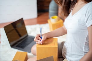 Unternehmerin Inhaberin KMU-Geschäft prüft Bestellung mit Smartphone, Laptop und Verpackungsbox, um ihren Kunden zu senden