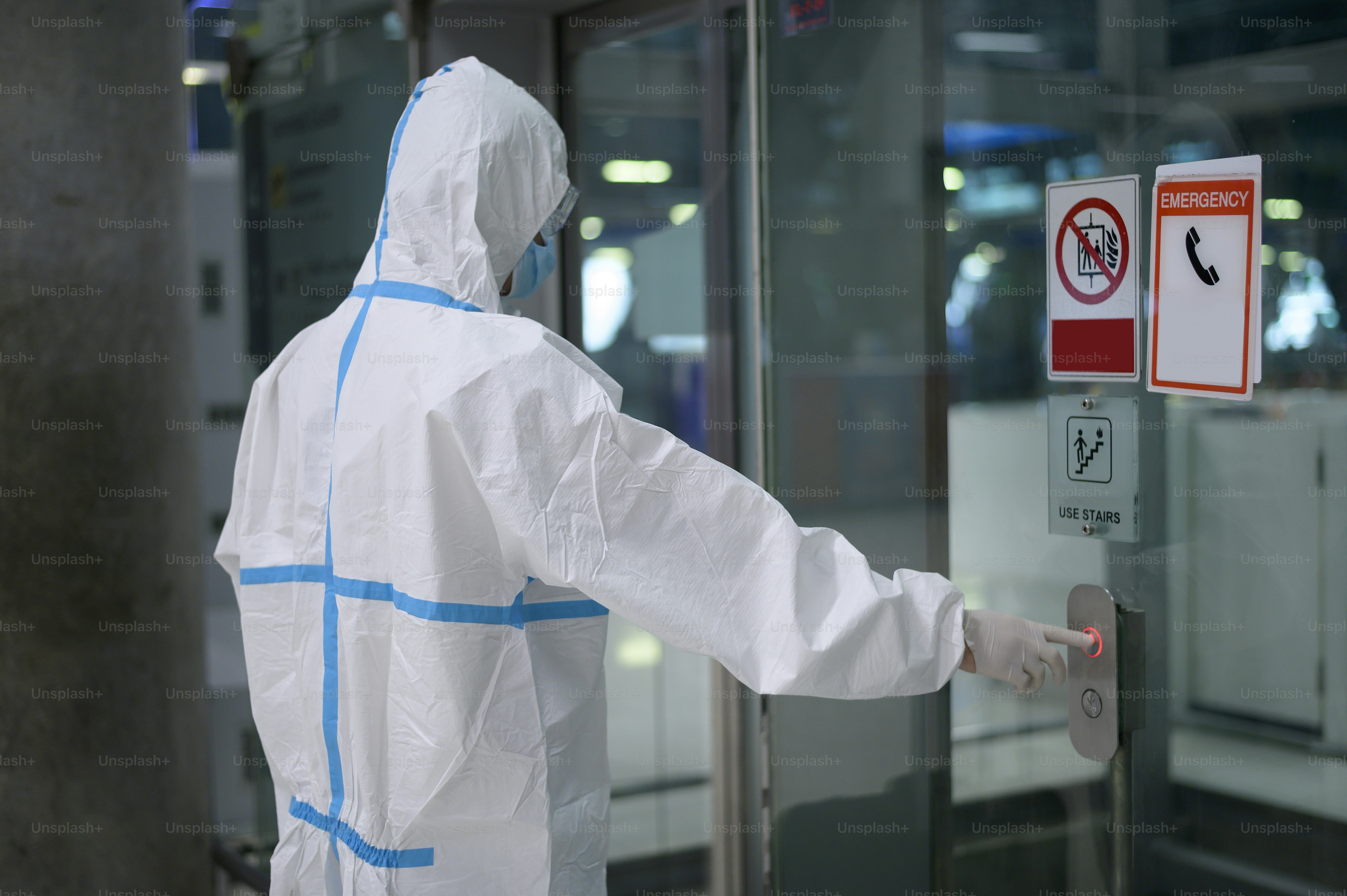 Ein asiatischer Mann trägt einen Psappenanzug im Flughafenaufzug, Sicherheitsreisen, Covid-19-Schutz, Social Distancing-Konzept.