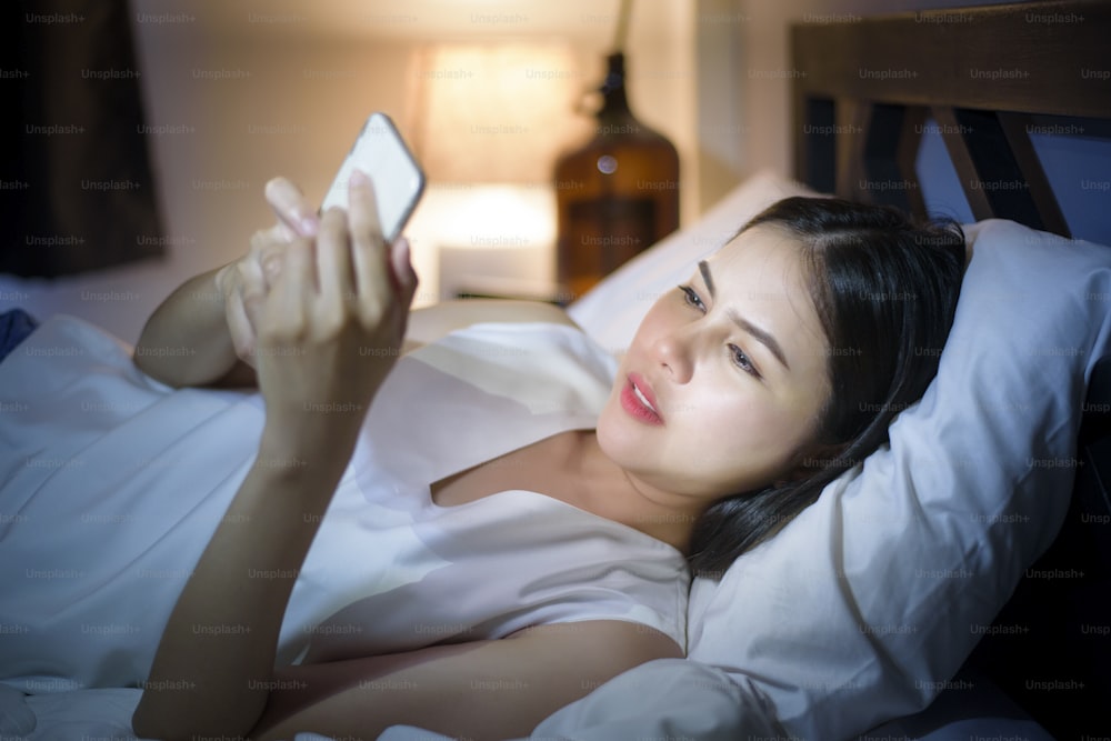 Frau fühlt Augenschmerzen, wenn sie nachts Smartphone benutzt