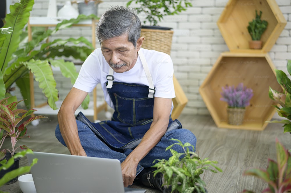 happy senior asian retired man with laptop  is relaxing  and enjoying  leisure activity in garden at home.