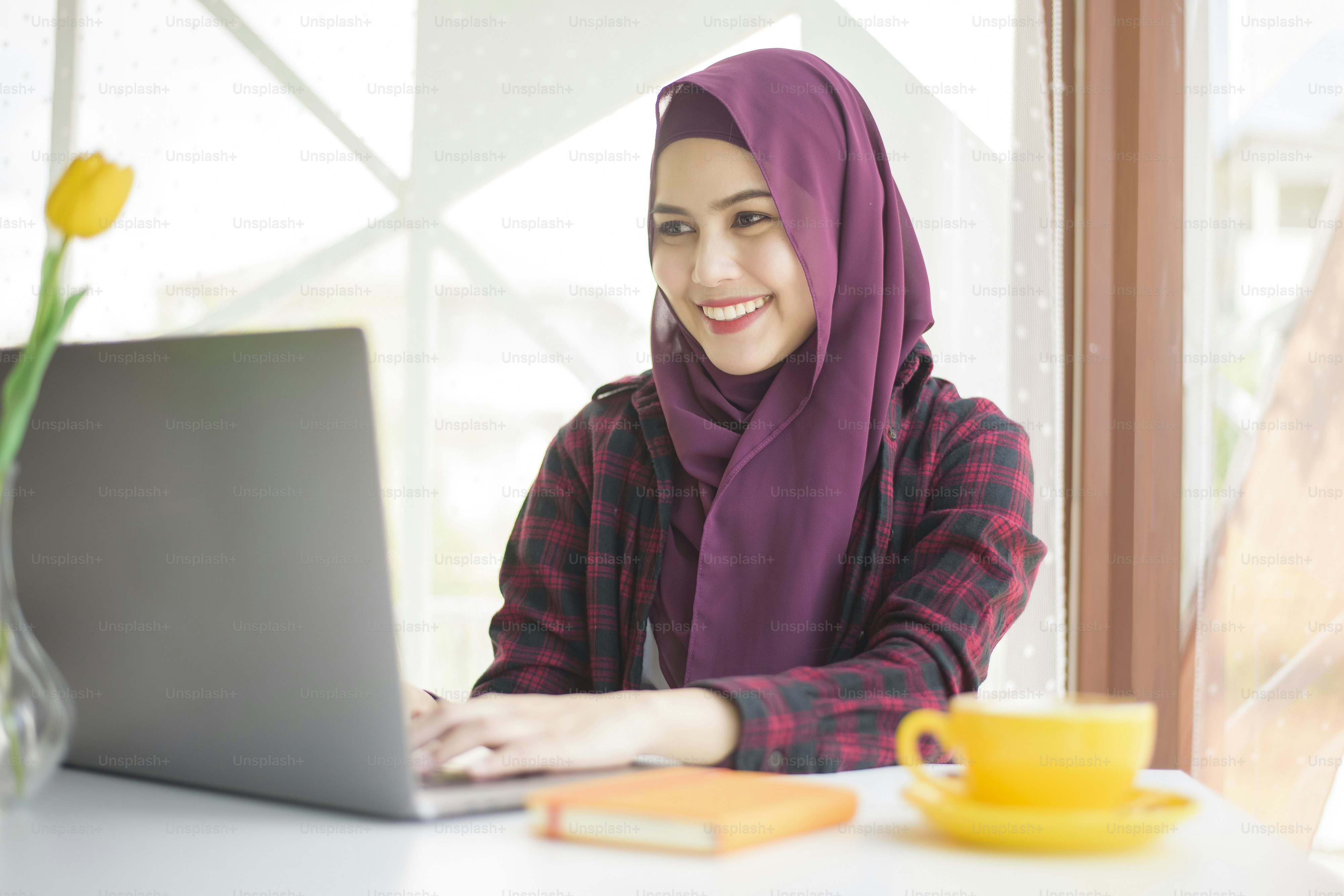 Muslim woman with hijab is working with laptop computer in coffee shop