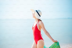 La bella donna in costume da bagno rosso si sta rilassando sulla spiaggia, concetto estivo