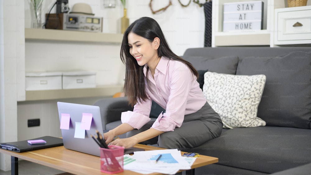 Una mujer de negocios está trabajando con una computadora portátil y analizando los datos del gráfico de crecimiento del negocio en la sala de estar, el trabajo desde casa, el concepto de tecnología empresarial.