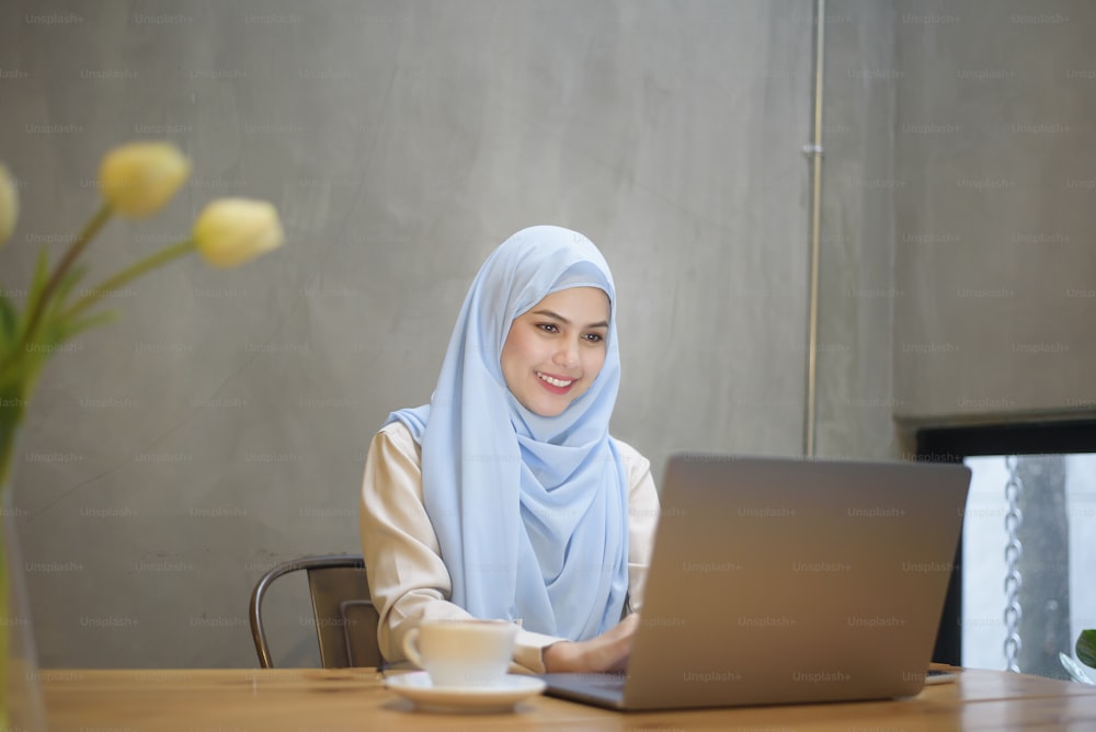 Muslim woman with hijab is working with laptop computer in coffee shop