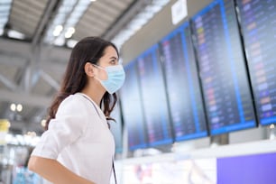 Una donna viaggiatrice indossa una maschera protettiva nell'aeroporto internazionale, viaggia sotto la pandemia di Covid-19, viaggi di sicurezza, protocollo di distanziamento sociale, nuovo concetto di viaggio normale.