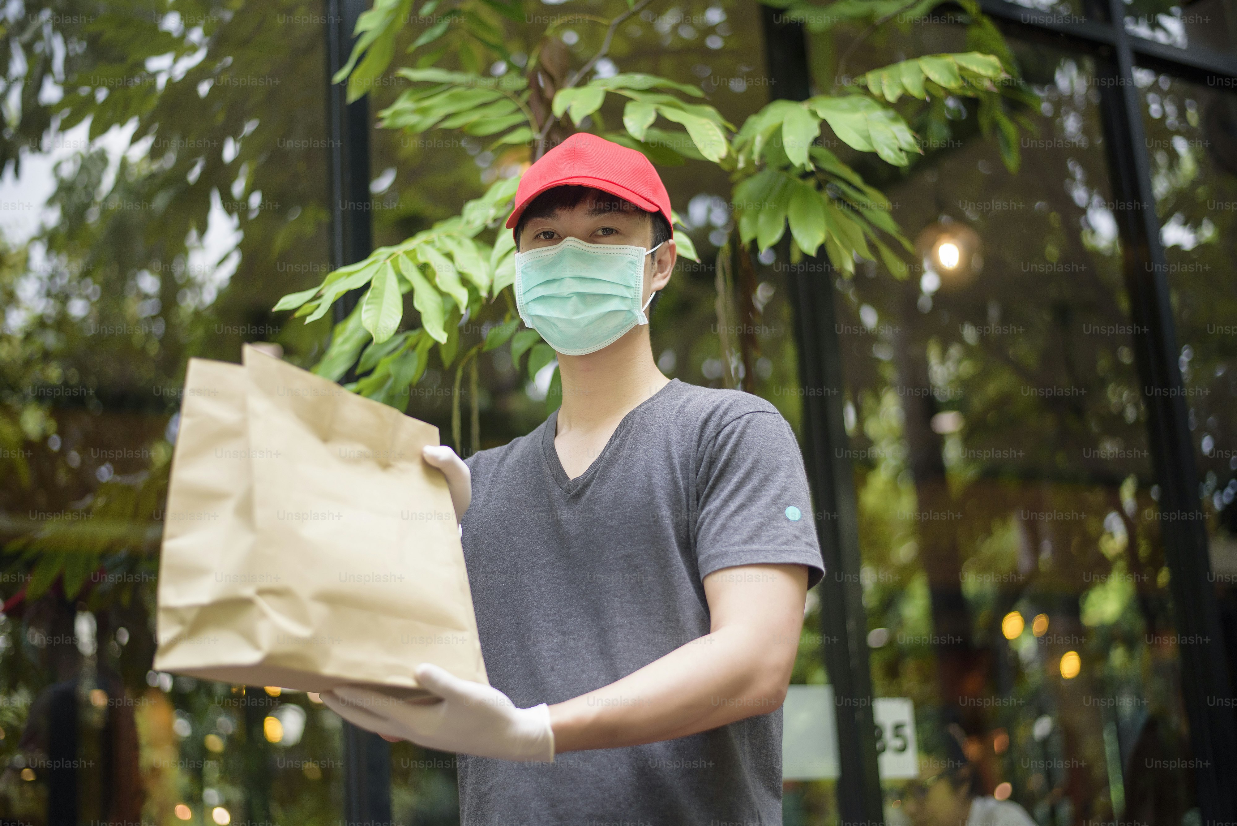 An Asian delivery man is wearing face mask, holding grocery bag ...