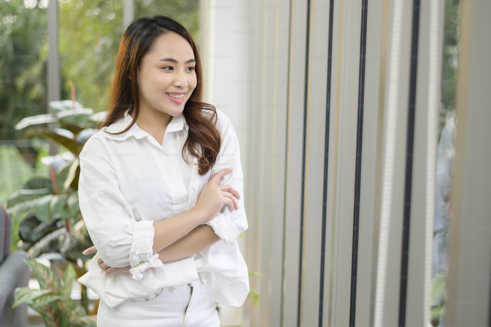 Ein Porträt einer selbstbewussten asiatischen Geschäftsfrau mit weißem Hemd im Büro