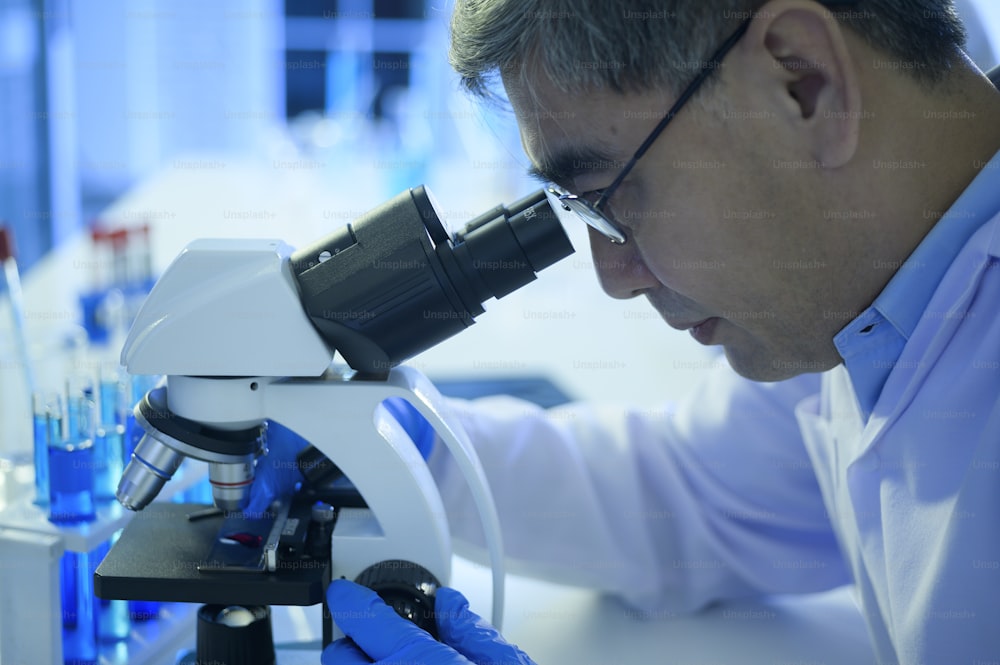 Um cientista usando microscópio durante experimento em laboratório, ciência e tecnologia conceito de saúde