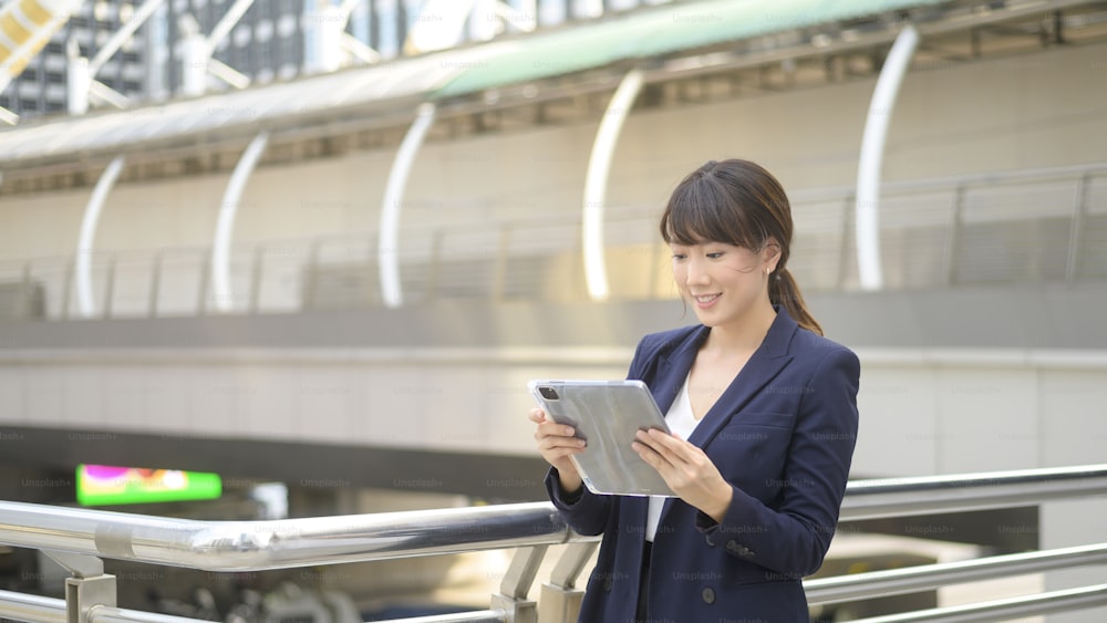 beautiful young asian business woman is using tablet in modern city