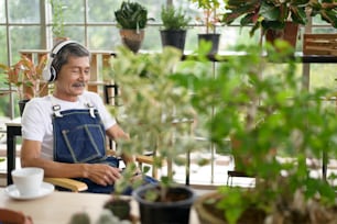 A happy senior asian retired man listening to music  and enjoying  leisure activity in garden at home.