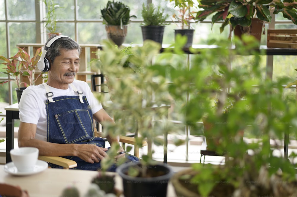 Um homem aposentado asiático sênior feliz ouvindo música e desfrutando de atividades de lazer no jardim em casa.