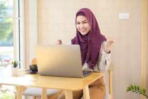Uma mulher de negócios muçulmana usando hijab trabalhando com seu laptop em uma cafeteria