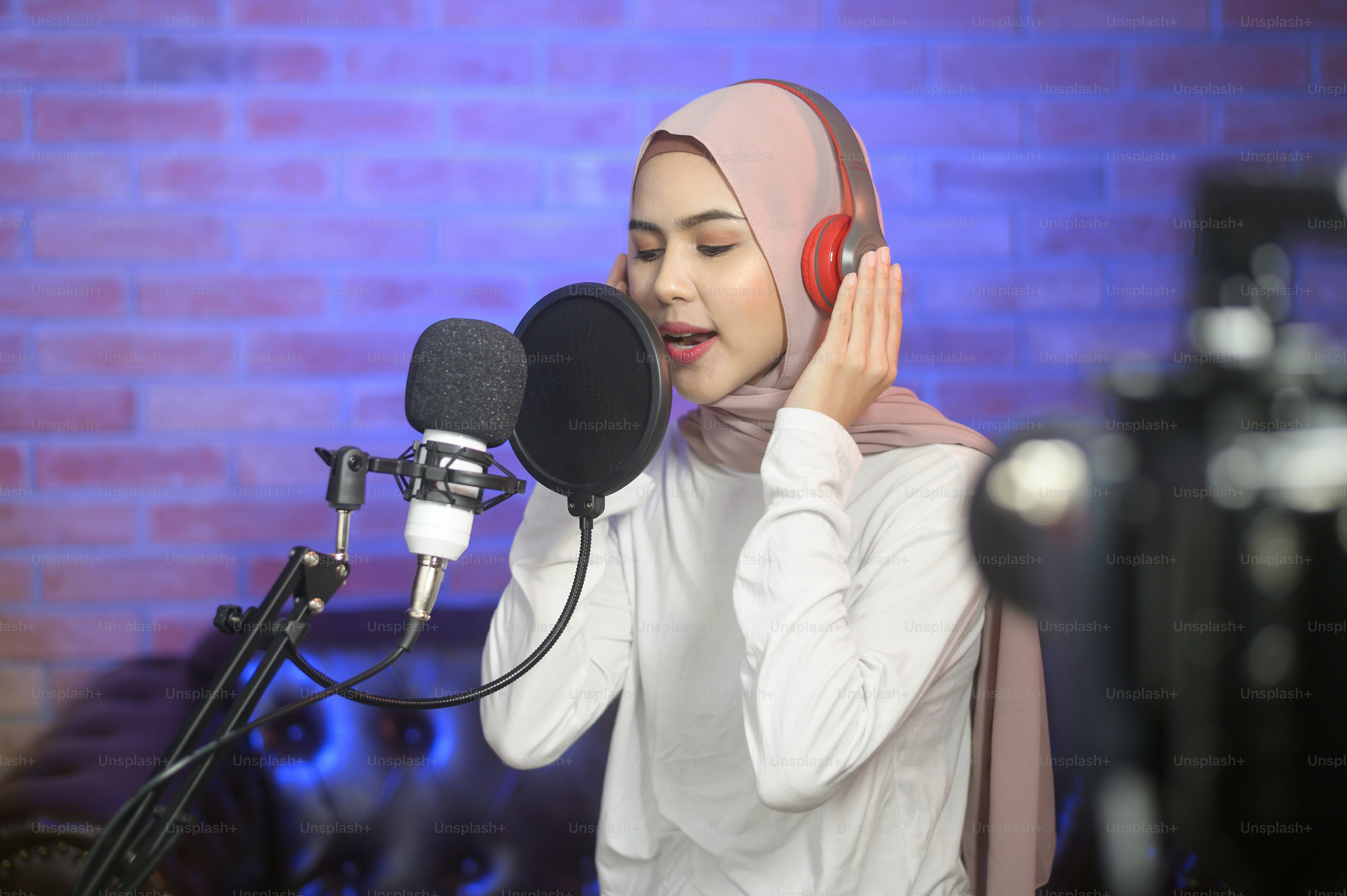 A young smiling muslim female singer wearing headphones with a ...