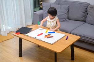 自宅のリビングで色鉛筆で絵を描いている女の赤ちゃん。