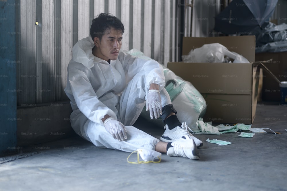 Lavoratore in DPI esausto e provato negli impianti di riciclaggio dei rifiuti durante il covid-19 e la pandemia.