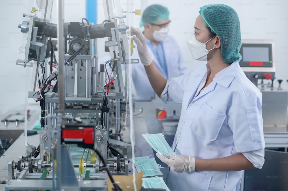 Trabajadores que producen mascarillas quirúrgicas en fábricas modernas, protección Covid-19 y concepto médico.