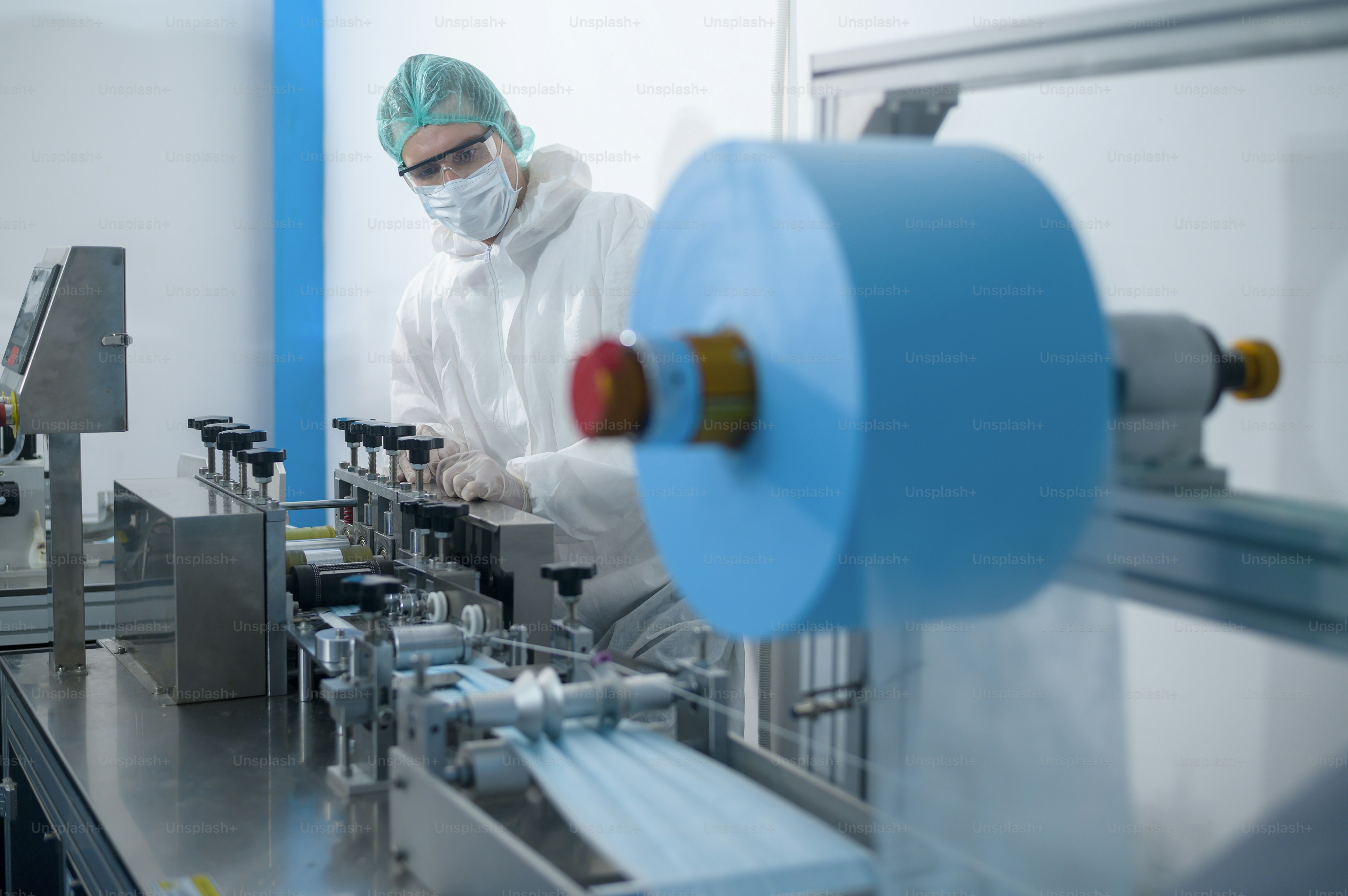 Workers producing surgical mask in modern factory, Covid-19 protection and medical concept.