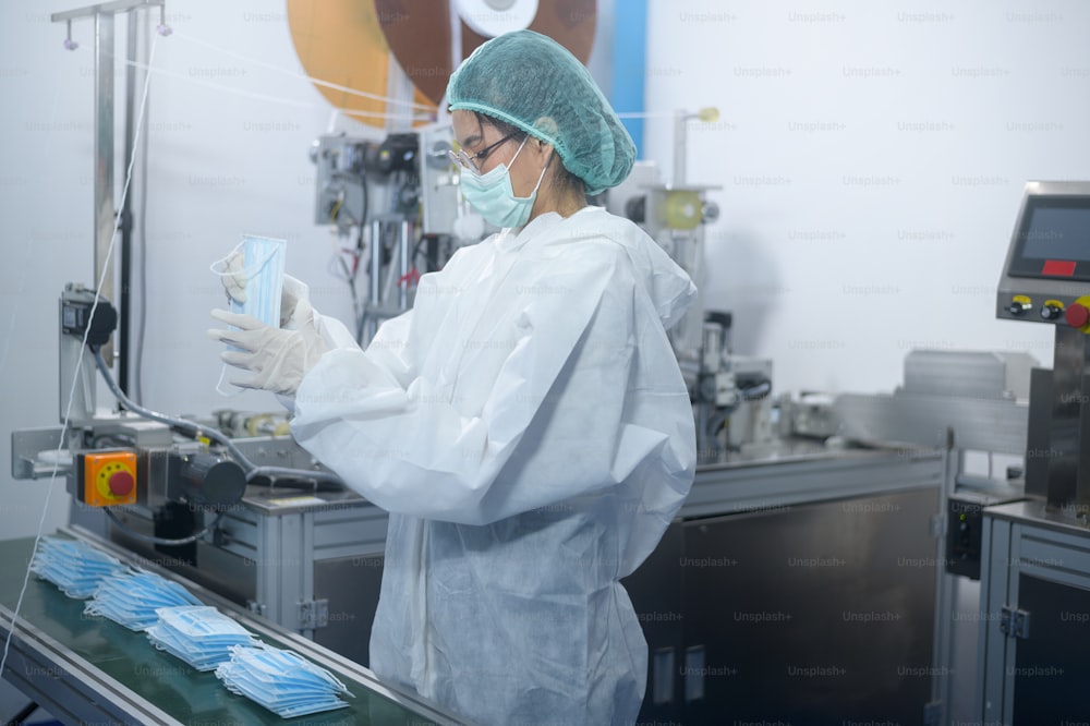Arbeiter, die chirurgische Masken in moderner Fabrik, Covid-19-Schutz und medizinisches Konzept herstellen.